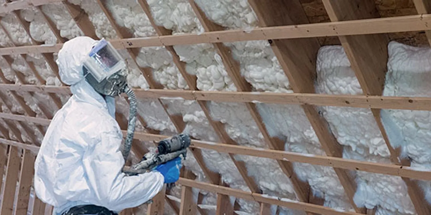 Installer spraying foam on a roof or wall assembly