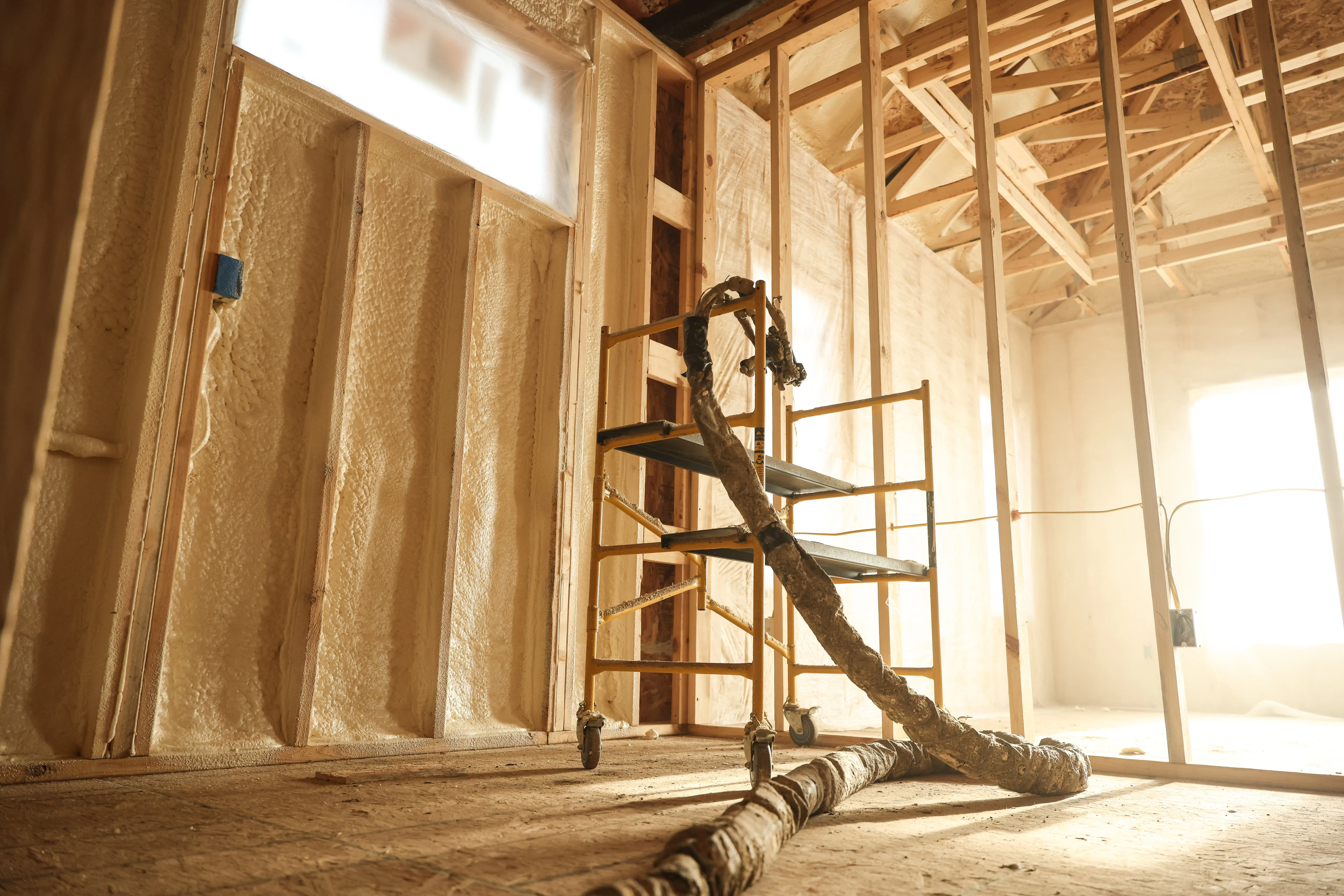Installer applying spray foam insulation inside a framed Central Florida building